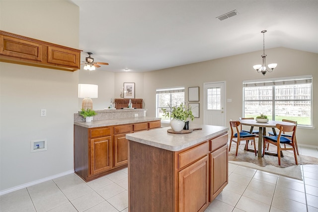 kitchen with ceiling fan with notable chandelier, light tile patterned floors, decorative light fixtures, and a kitchen island