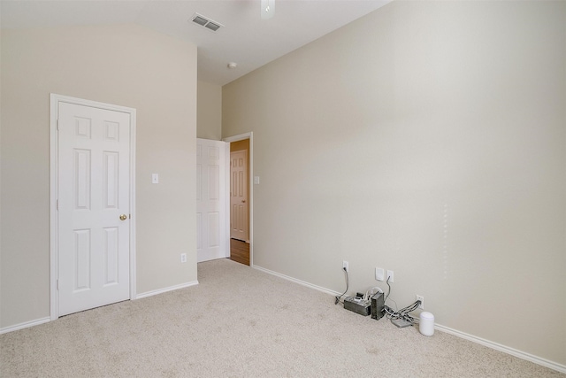 carpeted empty room with vaulted ceiling