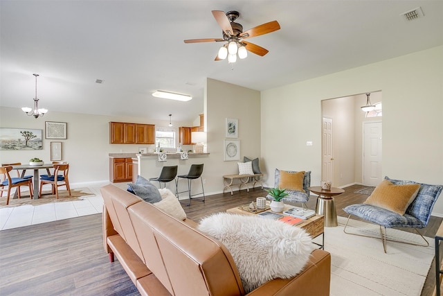 living room with hardwood / wood-style floors and ceiling fan with notable chandelier