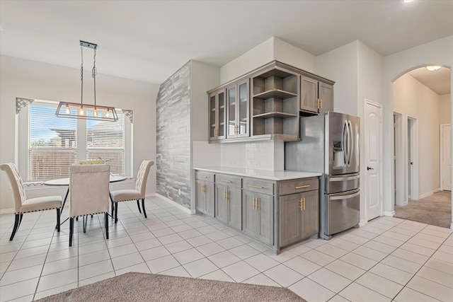 kitchen with stainless steel fridge, tasteful backsplash, light tile patterned floors, an inviting chandelier, and pendant lighting