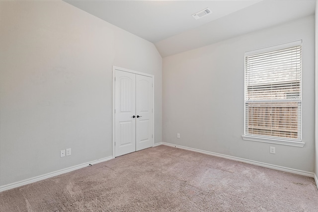 empty room featuring lofted ceiling and light colored carpet