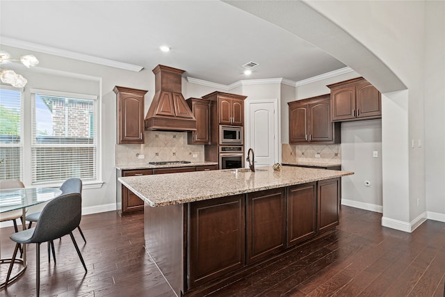 kitchen featuring dark wood-type flooring, stainless steel appliances, custom exhaust hood, and an island with sink