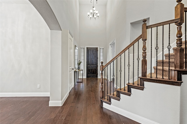 foyer with a towering ceiling, dark hardwood / wood-style flooring, and an inviting chandelier