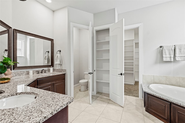 bathroom featuring vanity, a tub, toilet, and tile patterned flooring