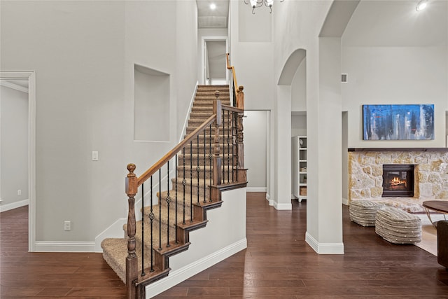 stairway with hardwood / wood-style flooring, a towering ceiling, and a fireplace