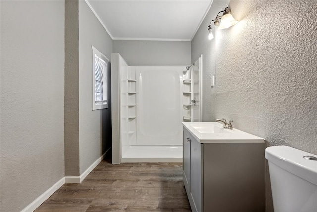 bathroom with vanity, ornamental molding, wood-type flooring, and toilet