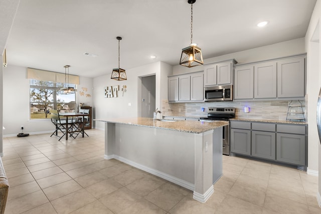 kitchen with gray cabinets, appliances with stainless steel finishes, sink, and a kitchen island with sink