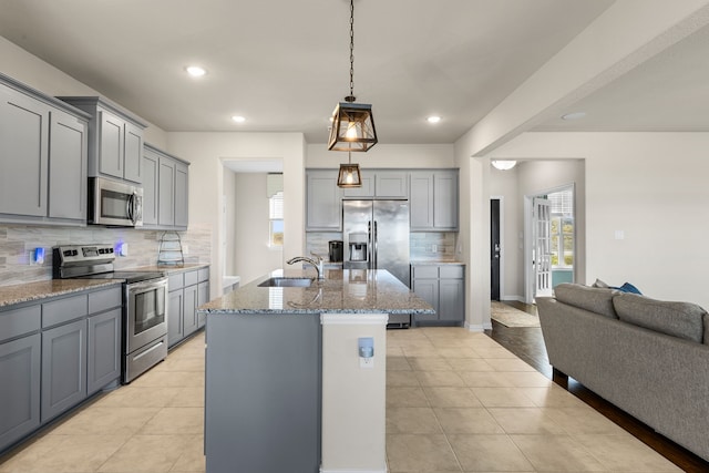 kitchen with a kitchen island with sink, gray cabinets, appliances with stainless steel finishes, and sink