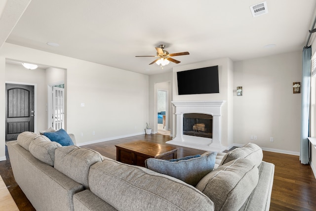 living room with dark wood-type flooring, ceiling fan, and a healthy amount of sunlight