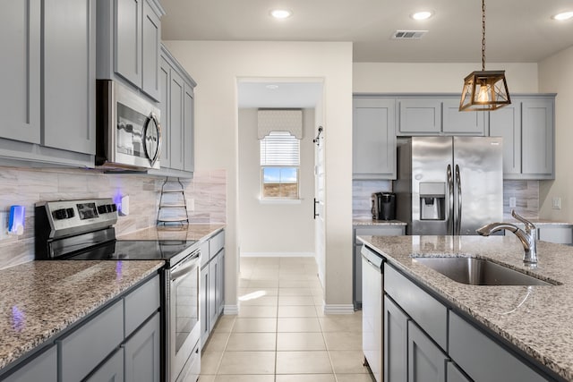 kitchen featuring gray cabinets, appliances with stainless steel finishes, sink, and light stone countertops