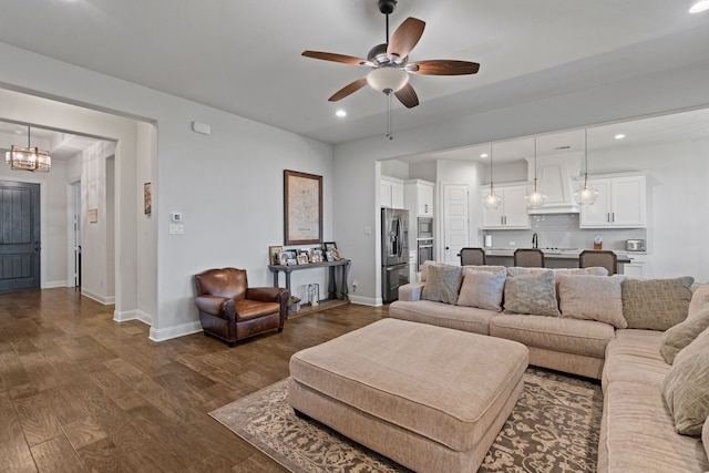 living room with ceiling fan with notable chandelier and dark hardwood / wood-style floors