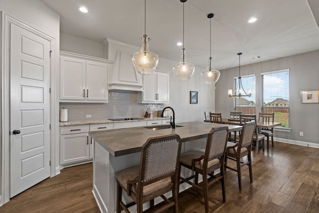 kitchen with sink, an island with sink, white cabinets, and decorative light fixtures