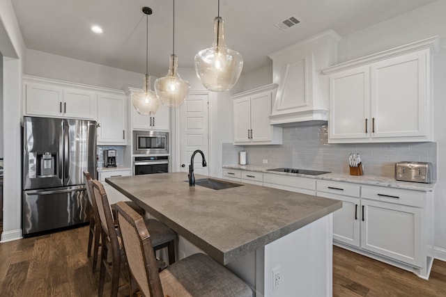 kitchen featuring appliances with stainless steel finishes, premium range hood, pendant lighting, white cabinets, and sink