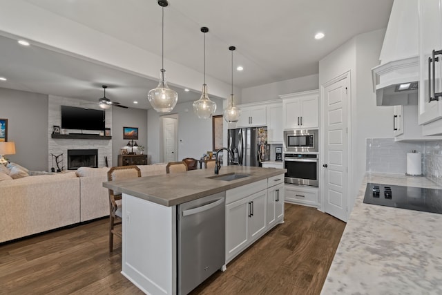 kitchen featuring stainless steel appliances, a center island with sink, a breakfast bar, and white cabinetry