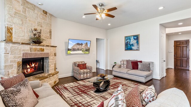 living room with dark wood-type flooring, a fireplace, and ceiling fan