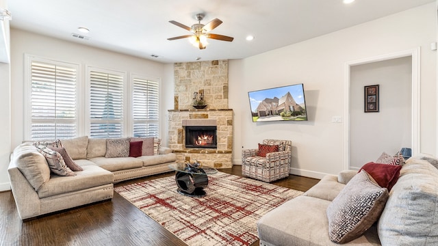 living room with a stone fireplace, ceiling fan, and dark hardwood / wood-style floors