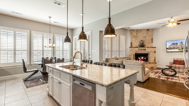 kitchen with a center island with sink, dishwasher, sink, white cabinetry, and light wood-type flooring