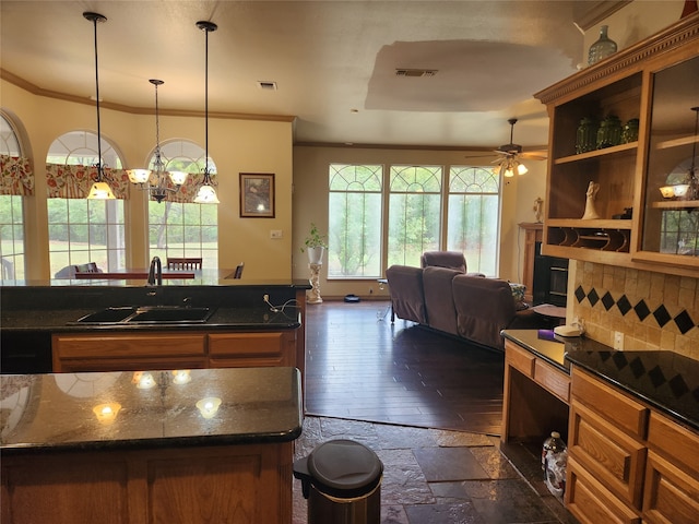 kitchen with dark hardwood / wood-style flooring, dark stone countertops, ceiling fan with notable chandelier, pendant lighting, and sink