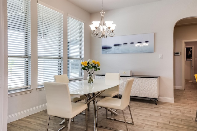 dining area with a notable chandelier and light hardwood / wood-style floors