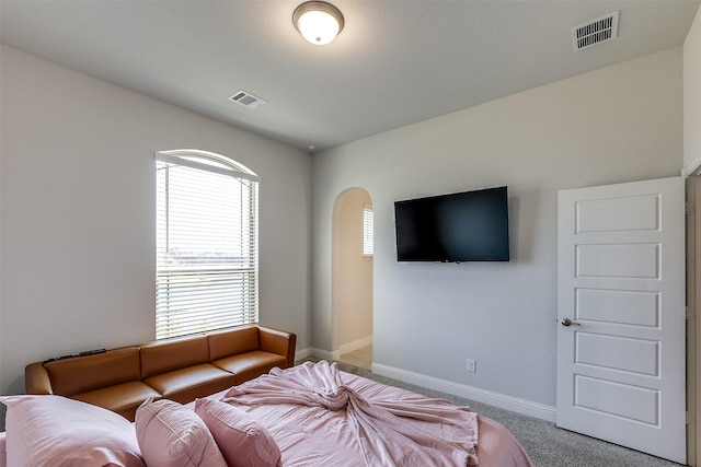 bedroom featuring arched walkways, carpet floors, visible vents, and baseboards