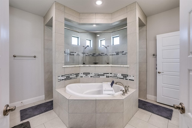 bathroom with a garden tub, tile patterned flooring, baseboards, and tiled shower