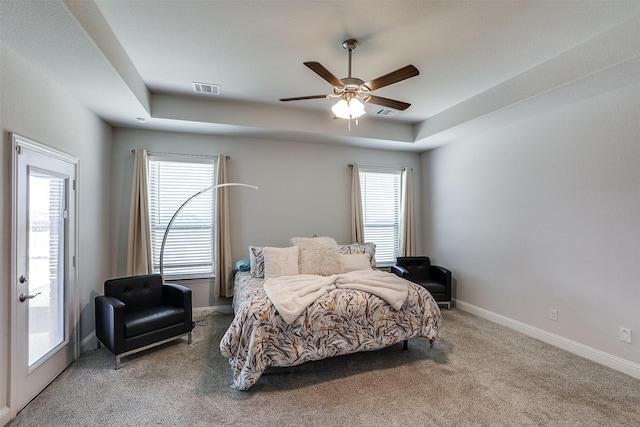 carpeted bedroom featuring ceiling fan, visible vents, baseboards, access to exterior, and a raised ceiling