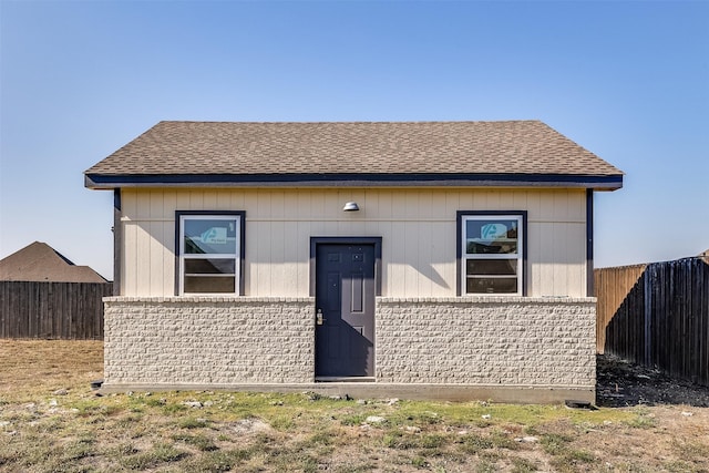 exterior space with brick siding, a shingled roof, and fence