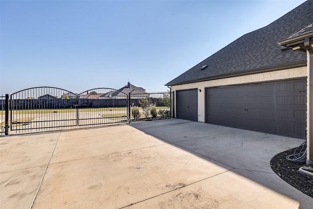 view of side of home with a shingled roof, a gate, and brick siding