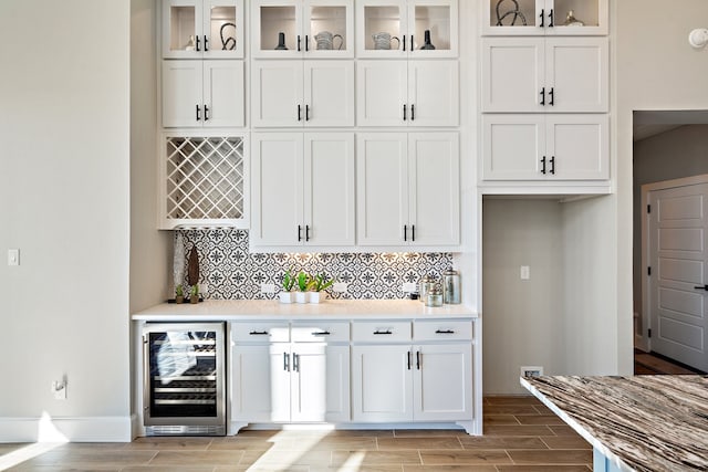 bar featuring white cabinetry, wine cooler, light hardwood / wood-style flooring, and backsplash