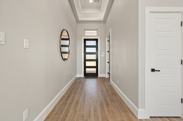 entryway with light hardwood / wood-style floors and a tray ceiling