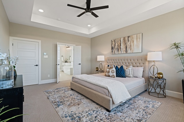 bedroom featuring connected bathroom, carpet, a raised ceiling, and ceiling fan