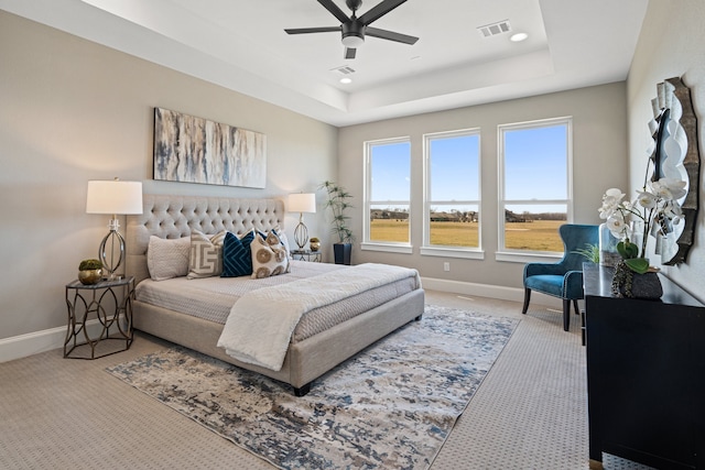 carpeted bedroom with a tray ceiling and ceiling fan