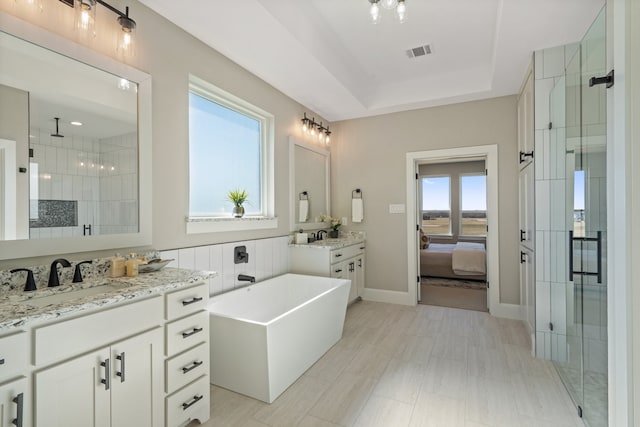 bathroom with vanity, a tray ceiling, and shower with separate bathtub