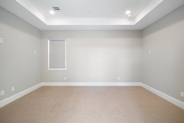 carpeted spare room with a tray ceiling