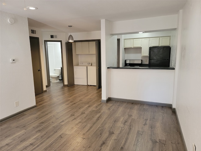 kitchen with black fridge, stainless steel range, hardwood / wood-style floors, decorative light fixtures, and washing machine and dryer