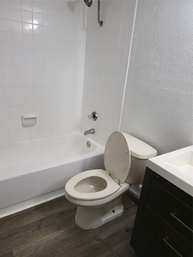 full bathroom with toilet, tiled shower / bath combo, hardwood / wood-style flooring, and vanity