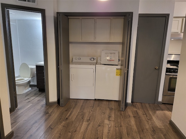 laundry room featuring cabinets, washer and clothes dryer, and dark hardwood / wood-style flooring