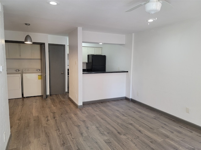 kitchen with hardwood / wood-style flooring, black fridge, decorative light fixtures, washer and dryer, and ceiling fan