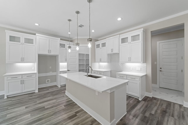 kitchen with white cabinetry, a kitchen island with sink, sink, and decorative light fixtures