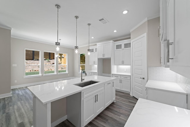 kitchen featuring light stone countertops, a kitchen island with sink, sink, and white cabinets