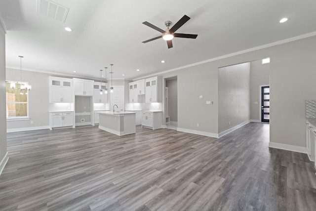 unfurnished living room featuring dark wood-type flooring, crown molding, and ceiling fan with notable chandelier