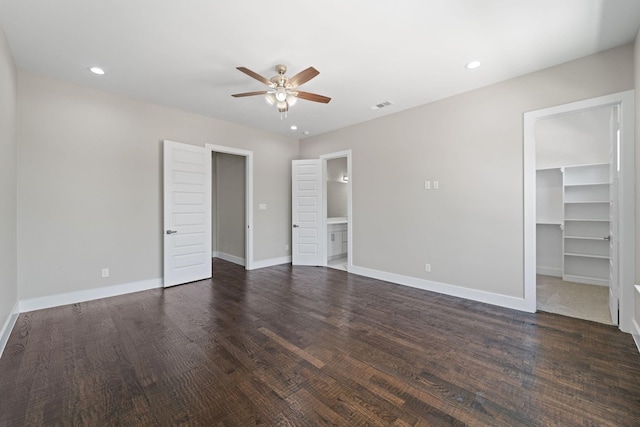 unfurnished bedroom featuring dark wood-type flooring, connected bathroom, a spacious closet, a closet, and ceiling fan