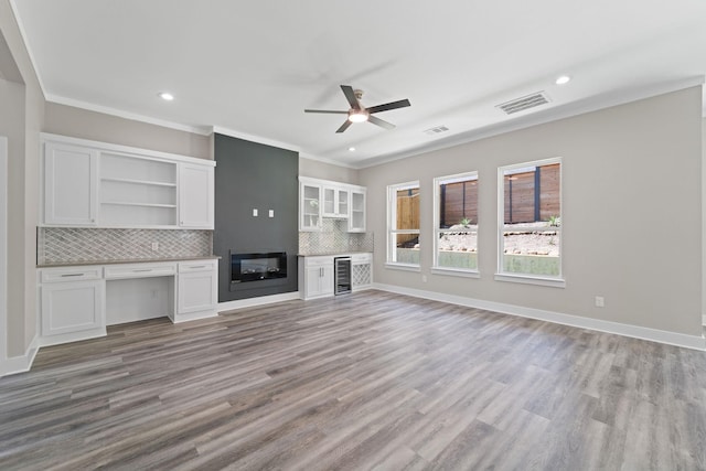 unfurnished living room featuring light hardwood / wood-style flooring, ceiling fan, wine cooler, a fireplace, and ornamental molding