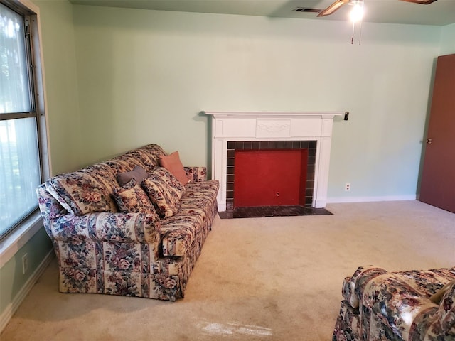 living room with ceiling fan, carpet floors, and a tile fireplace