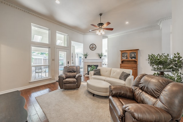 living room featuring crown molding, a fireplace, ceiling fan, and wood-type flooring