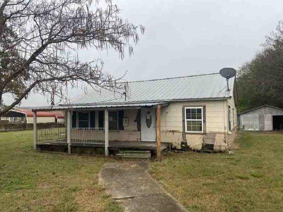 view of front of house with a front yard, covered porch, and a shed