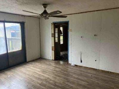 unfurnished room with ceiling fan, wood-type flooring, and a textured ceiling