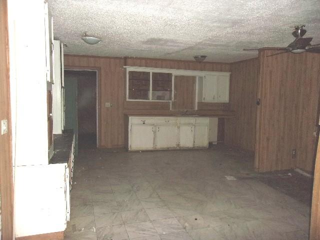 11114 E State Highway 31, Kerens, TX 75144 - kitchen with wooden walls, ceiling fan, light flooring, and white cabinets
