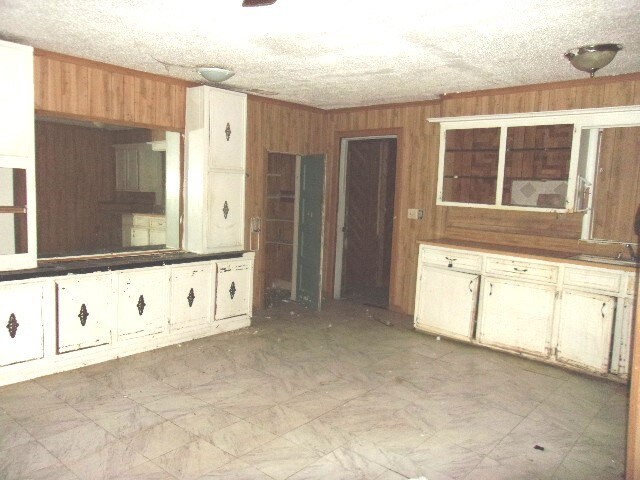 kitchen with a textured ceiling and wood walls