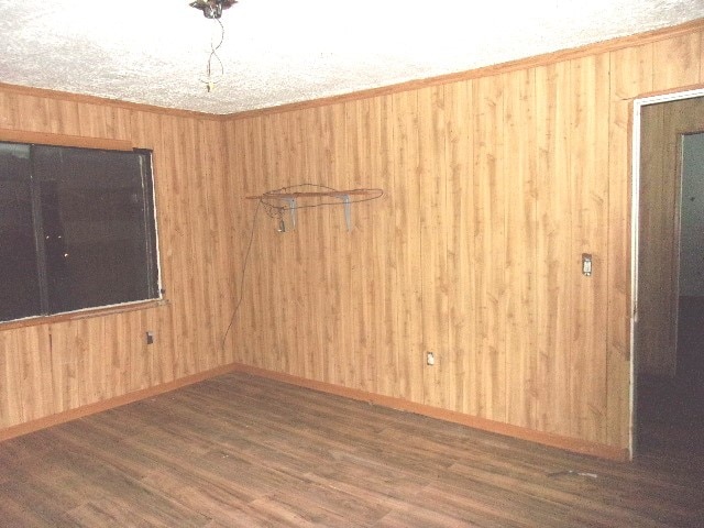 empty room with wooden walls and dark hardwood / wood-style flooring